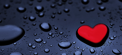 Raindrops on a blue background, but one drop is shaped and colored like a heart.