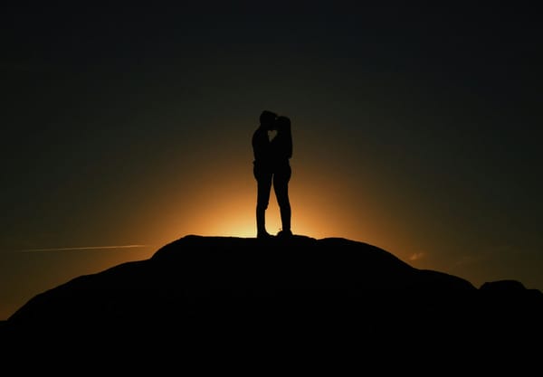 A couple embracing against a sunrise.