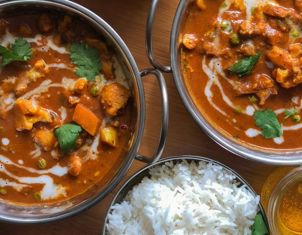 Two pots of golden curry, and a bowl of white rice.