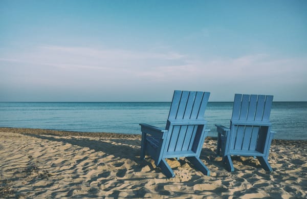 Two empty beach chairs on a beach, overlooking the ocean.